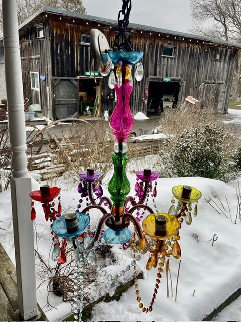 Colorful hanging chandelier outdoors with a rustic barn in the background.