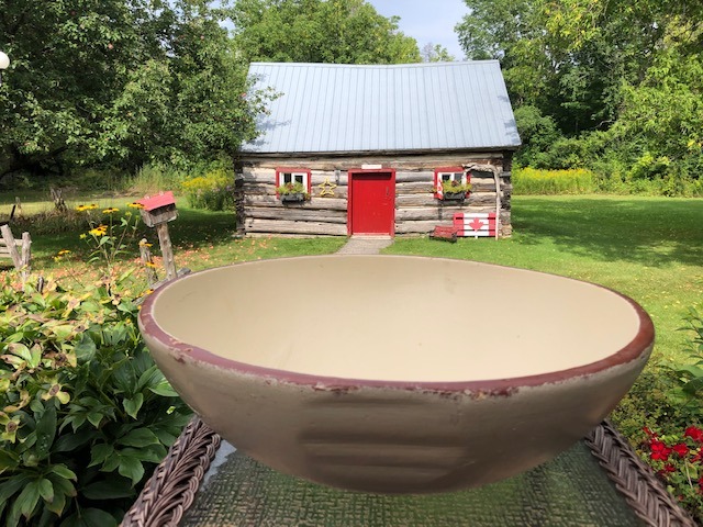 beige ceramic bowl on top of a table with wooden house in the background