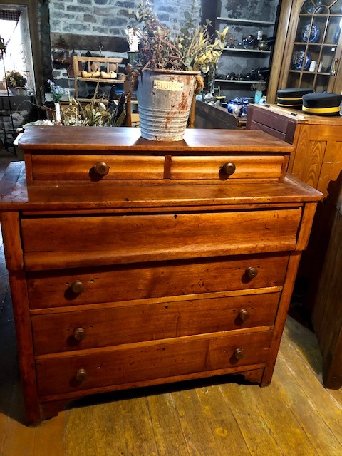 brown 4 layer drawer with additional 2 drawers on top and a bucket of dried plant