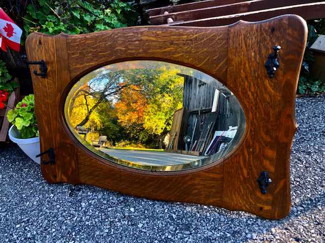 oval mirror set in wooden rectangular frame with clothes hooks in each corner