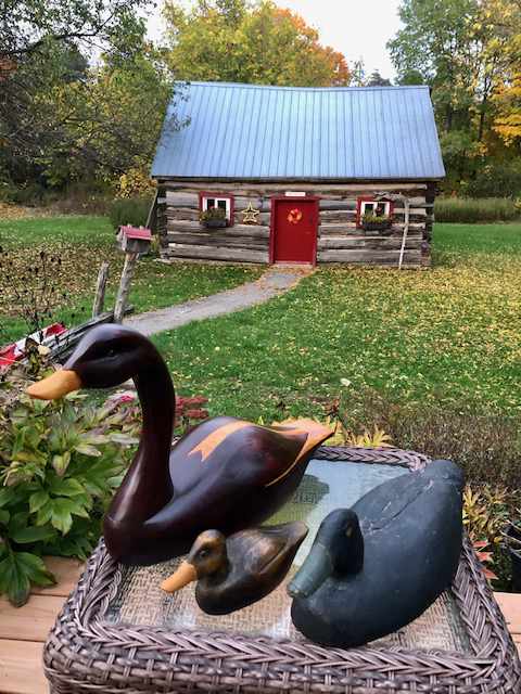 wooden carved ducks on a wicker table with glass top