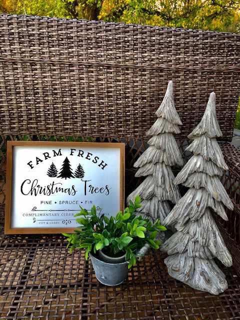 a sign for "farm fresh christmas trees" next to two ceramic christmas trees and a green plant in a metal holder