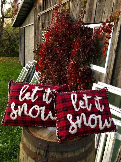 two red tartan cushions with "let it snow" embroidered on them