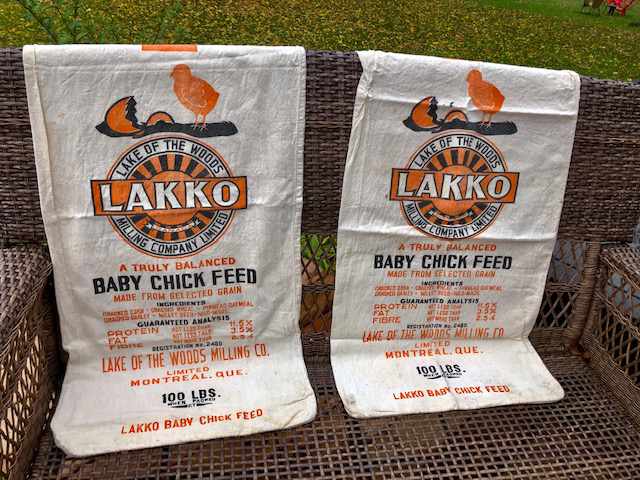 two lacko 100lbs chick feed cloth bags draped over a wicker couch