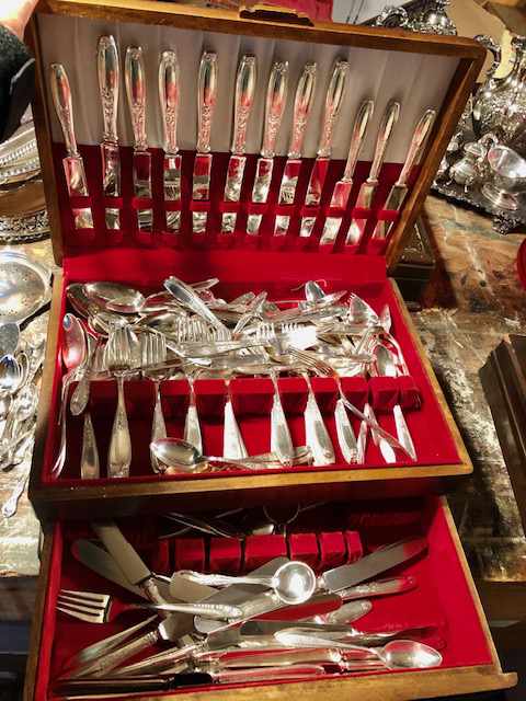 a three layer cutlery case holding a variety of silver cutlery
