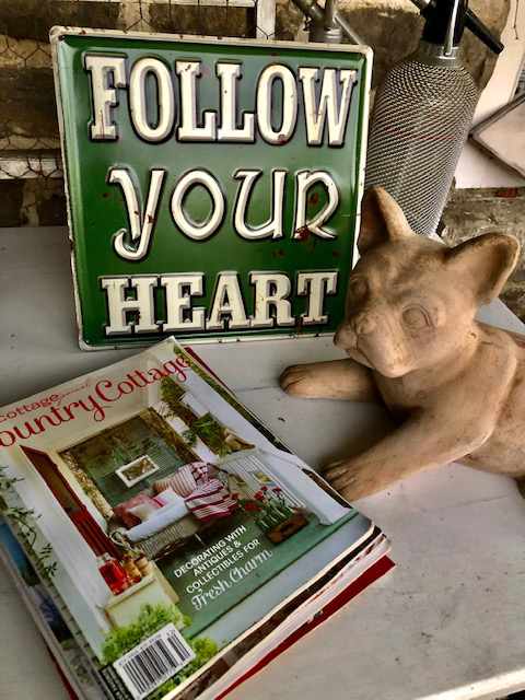 ceramic dog in front of a "follow your heart" sign