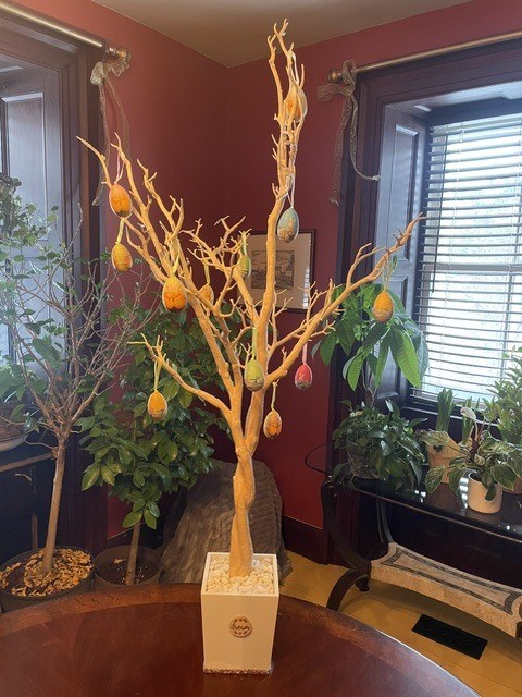 Decorative indoor tree with hanging colorful egg ornaments in a cozy room.