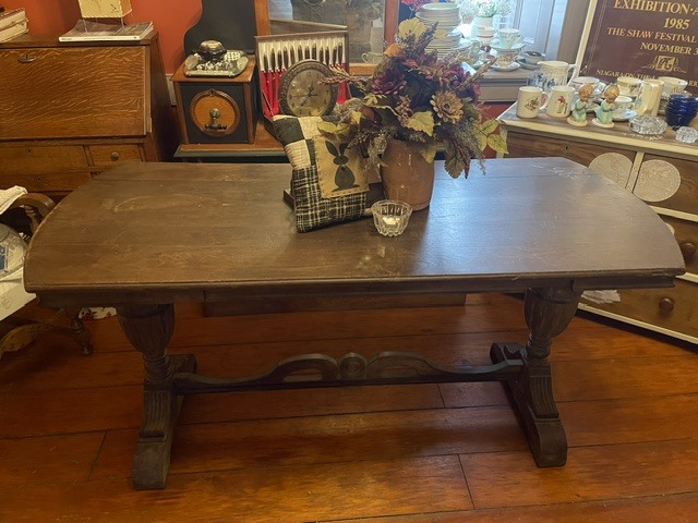 Dark wooden dining table with a floral centerpiece in a vintage-style room.