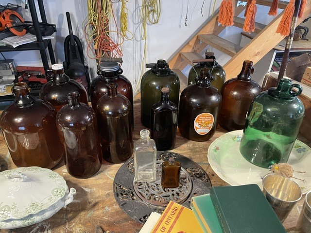 Collection of vintage glass bottles and jars on a worktable.
