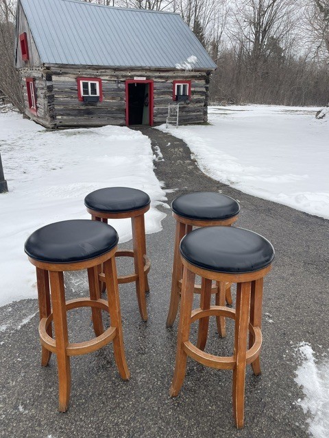 Four wooden bar stools on a snowy path