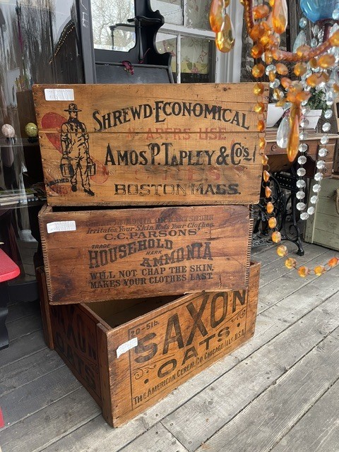 Stacked vintage wooden crates with printed labels on a porch.
