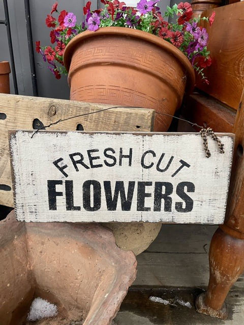 “Fresh Cut Flowers” sign with a terracotta pot of blooming flowers.